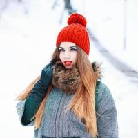 Young beautiful girl with a red hat and coat in winter snowy day photo