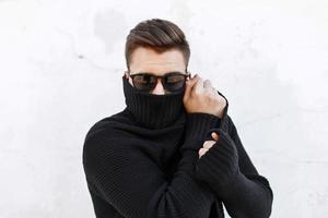 Young fashionable guy in black sunglasses vite and covers the face with a cloth. photo