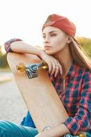 Pretty woman with skateboard in autumn day. On the background of a beautiful sunset. photo