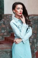 Beautiful pretty woman in a denim jacket and turquoise dress near stone photo