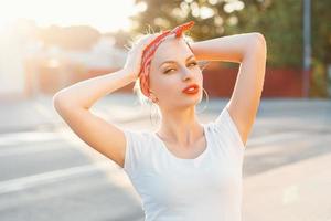 Beautiful girl in retro style with red lips and a bandage on head. sunset photo