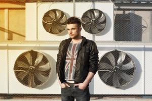 Beautiful guy in a black leather jacket. Stands near blades. photo