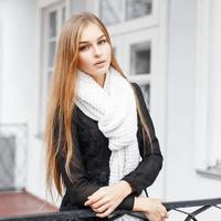 Young beautiful girl with a warm knitted scarf standing on the porch of vintage homes photo