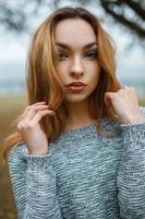 retrato de primer plano de una hermosa joven con elegante suéter de invierno en el fondo de un árbol con niebla foto