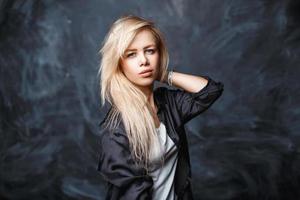 retrato de una hermosa joven con cabello rubio en una camisa negra y una camisa blanca sobre un fondo oscuro con manchas foto