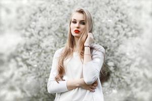 Portrait of young woman near blossoming tree. Red lips. photo