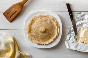 Appetizing pancakes with butter on a wooden table. The knife, vane and the fabric, the top view. photo