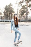 Stylish young girl rides a skateboard at sunset photo