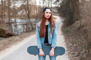 niña sosteniendo una patineta en el fondo del parque de primavera foto