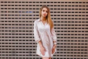 Young beautiful girl in a shirt posing near the wall. photo