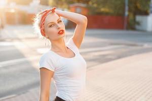 Beautiful girl in retro style with red lips and a bandage on head. sunset photo