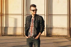 Hipster in a black leather jacket and sunglasses. Outdoors sunset portrait. photo