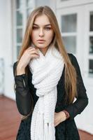 Fashionable stylish girl with a white scarf is a warm on the background of retro building photo