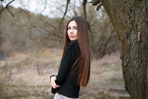 Beautiful young girl standing near a tree in the garden background. photo