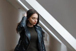 hermosa chica con una chaqueta negra cerca de una ventana en la habitación foto