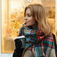 Close-up portrait of a sweet girl with a coffee on a background of lights photo