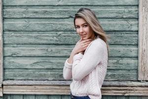 Beautiful young girl on the background of an old wooden wall with a scuffed photo