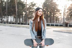 hermosa chica elegante hipster con monopatín en un día soleado foto