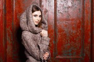 Fashionable Stylish young girl in jacket with hood standing near red  vintage wall photo