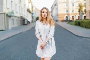 Pretty young girl in fashionable clothes standing on the road. photo