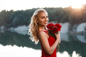 Portrait of a happy pretty woman with a bouquet of peony. On the background of the sea. Sunset light photo