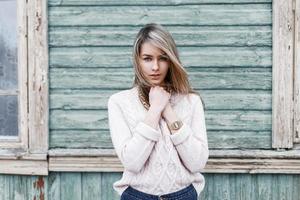 Modest young girl on the background of the old wooden wall with windows photo