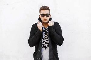 Young handsome man in sunglasses and a sweater on a white background. photo