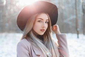 retrato de una joven hermosa con un sombrero negro en un día de invierno al atardecer