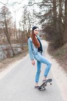 Young beautiful girl with skateboard standing on the asphalt path. photo