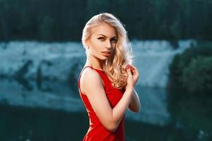 Pretty woman in red dress standing near the mountain. sunset photo