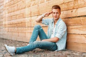 Young man posing by the wooden wall. Guy saluting. photo