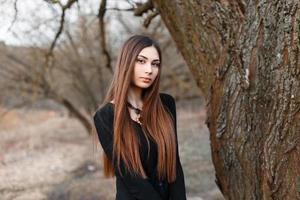 Beautiful young girl in black blouse on a park background. Early spring photo