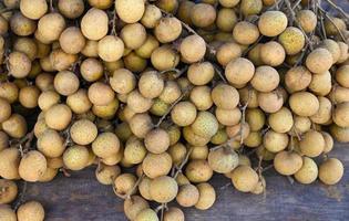 Longan fruits on wooden background, bunch of fresh longan tropical fruit in Thailand - Dimocarpus longan photo