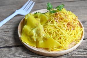 yellow noodles on white plate and pork dumplings wooden background , instant noodles yellow noodles rice vermicelli food with fried garlic photo