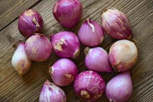 chalotes o cebolla roja, chalotes morados sobre fondo de madera, chalotes frescos para productos medicinales o hierbas y especias comida tailandesa hecha con este chalote crudo foto