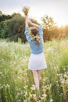 Beautiful girl  walking on field on summer with wildflowers. photo