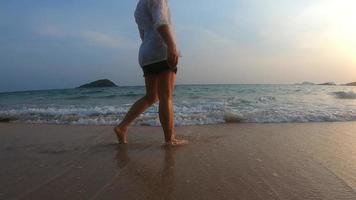 donna felice al rallentatore che cammina sulla bella spiaggia di sabbia pulita con sfondo tramonto - silhouette persone al concetto di vacanza spiaggia natura video