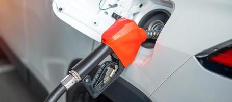 Man hand refuel to car, gasoline fuel nozzle in vehicle at petrol station. Oil Price, petroleum economy, inflation and commodity concept photo
