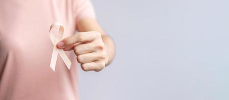 woman hand holding Peach Ribbon for September Uterine Cancer Awareness month. Healthcare and World cancer day concept photo