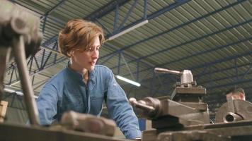 la giovane lavoratrice professionista dell'industria femminile bianca lavora in uniforme di sicurezza con strumenti di precisione per la lavorazione dei metalli, macchine per tornio meccanico e officina di pezzi di ricambio nella fabbrica di produzione dell'acciaio. video