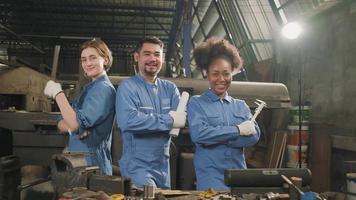 los trabajadores de la industria multirracial con uniformes de seguridad colaboran con unidad, se cruzan de brazos y expresan un trabajo feliz junto con una sonrisa y alegría en la fábrica mecánica, ocupación de ingeniero profesional. video