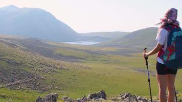 bakifrån passform sportig kvinnlig vandrare med stavgångstavar stå på utsiktspunkt uppför i grön vandringsled i Kaukasusbergen. fritidsaktiviteter och hälsosam livsstil video