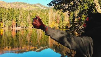 Cerrar mujer caucásica de pie junto al lago tomando una foto panorámica de la pintoresca naturaleza otoñal al aire libre video