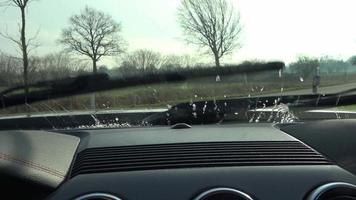 View at the windshield of a sports car from inside while the wipers cleaning the front windshield. video