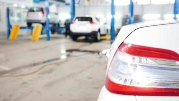 Automobile service - mechanics checking lifted car, de-focused time-lapse, wide angle video