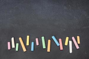 Variation of colored chalk sticks on blackboard. Copy space. Back to school photo