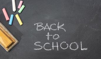 Group of Colored chalk, eraser and hand drawn phrase Back to School on blackboard photo