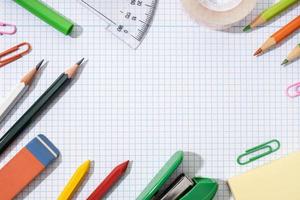 Frame of School and office supplies on blank graph paper sheet. Back to school background. Flat lay template mock up photo