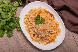 arroz frito con huevo de comida tailandesa en un plato blanco sobre un piso de madera foto