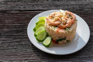 Thai fried rice with prawns and vegetables on wooden table photo